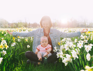 Mother and baby girl in spring park among blossom field