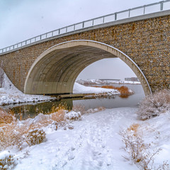 Arched bridge over lake and trail in winter