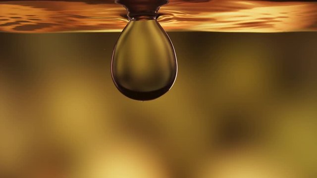 Pure, virgin vegetable canola oil with a large drop dipping, slow motion
