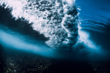 Wave underwater with air bubbles and sun light. Ocean in underwater