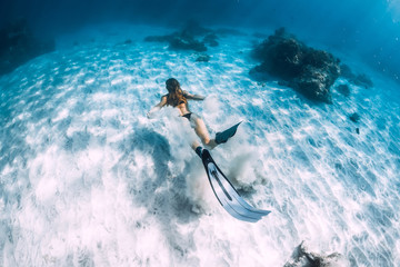 Woman freediver with sand over sandy sea with fins. Freediving underwater in Hawaii