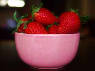 Pink strawberry bowl over dark table.