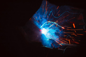 Arc welding. Welding of two metal plates in inert gases. MIG / MAG. A bright flash of light and a sheaf of sparks.