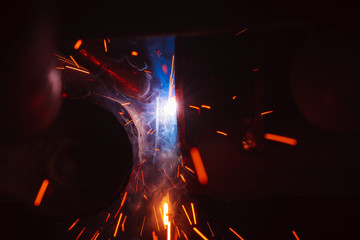 Fototapeta na wymiar Arc welding. Welding of two metal plates in inert gases. MIG / MAG. A bright flash of light and a sheaf of sparks.