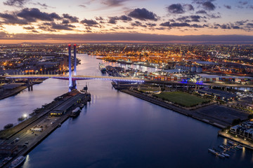 Aerial view of the Bolte Bridge in Melbourne Australia at sunset, with the industrial port in the...