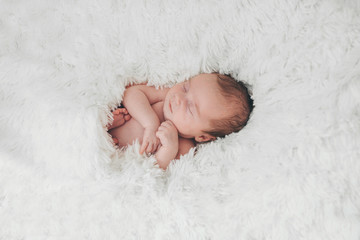 naked newborn baby sleeping curled up in a ball