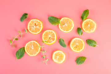 Yellow lemon slices with mint leaves on pink background
