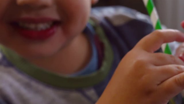 toddler holding paper straw while drinking