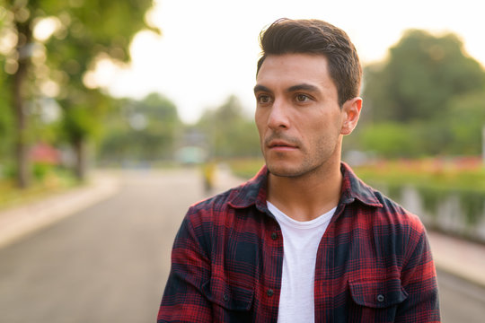 Face of young Hispanic hipster man thinking at the park - Powered by Adobe