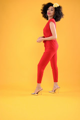 Young African American Woman in Red Jumpsuit on Yellow Background