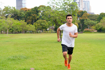Young handsome Hispanic man jogging at the park outdoors