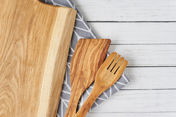 Kitchen utensils, cutting board, spatula and towel on a white wooden background