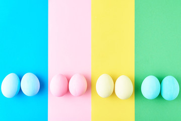 Eggs on colored striped background, top view, minimalism concept