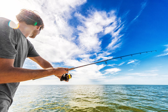 Man fishing in the sea from boat casting bait throwing line.