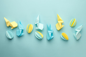 Creative Top view flat lay holiday composition Easter eggs funny bunny on blue paper background, copy space. Origami papercraft Easter day seasonal pattern