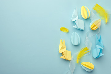 Easter holiday creative background with papercraft eggs, origami bunny on pastel blue table, trendy paper craft holiday background, top view, copy space