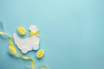 Easter holiday creative background with papercraft eggs, white wooden chicken hun on pastel blue table, trendy paper craft holiday background, top view, copy space