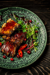 Smoked beef ribs cut in sour sweet berry sauce served with green seedlings. Tasty snack served with green seedlings on the plate. concept of Asian cuisine. restaurant serving, place for text