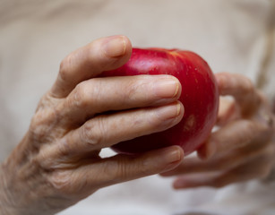 Elderly Caucasian Woman Holding a Ripe Red Apple