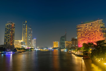 Cityscape riverfront with long exposure light on the bridge. Bangkok, Thailand.