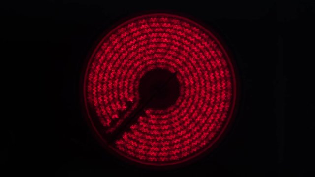 Modern electric stove is heated to red. Electric stove powered up red hotplate glows red on-black background.