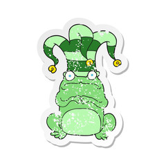 retro distressed sticker of a cartoon nervous frog wearing jester hat