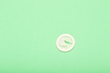 Opened condom and condom in pack on a green background. A condom use to reduce the probability of pregnancy or sexually transmitted disease (STD). Safe sex and reproductive health concept.