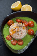 Close-up of baked hake medallions with green peas puree and cherry tomatoes, vertical shot