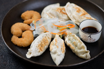 Fried korean potstickers with king shrimps in panko breading and noodles salad, close-up, selective focus
