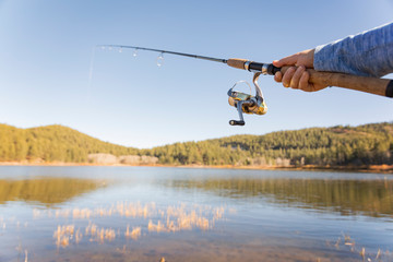 Fishing rod in angler's hand on small calm lake