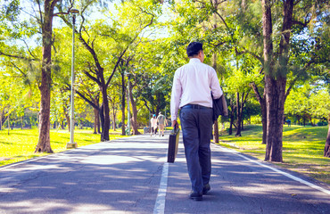 Businessman walking on road in park. He is drinking coffee and holding business bag. Photo concept business bag and relax time.