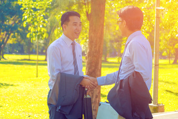 Businessman, They are shake hands  in park. They are talking  business. He is holding business bag. Photo concept  business and team work.
