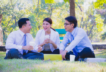 Business team work. They  are talking in the park.  they are talking about business and  on the floor had a notebook and a glass of coffee.Photo concept  business and relax time.