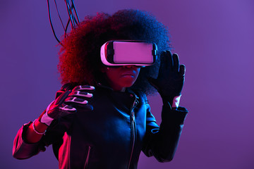 Mod curly dark haired girl dressed in black leather jacket and gloves uses the virtual reality...