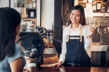 woman barista talking with customer about tasted of coffee cup with happy emotion at counter bar at...