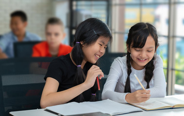 Asian students have fun writing on the notebook in classroom