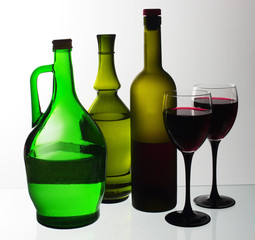 Two glasses of wine and bottles of wine and gin on the light.