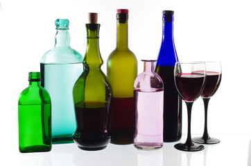 Two glasses of wine and bottles of wine and gin on the light.
