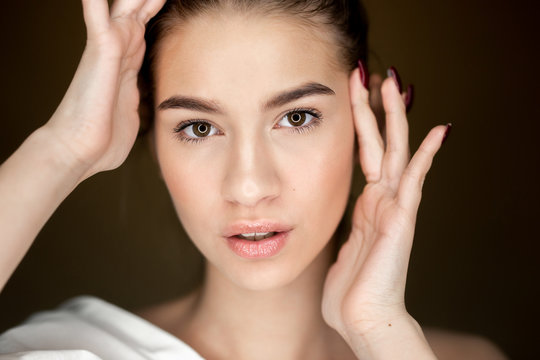 Portrait of young beautiful girl with natural makeup holding her hands on her head
