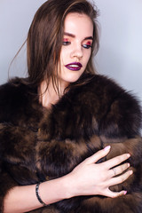 Beauty portrait of a woman with bright colorful make-up dressed in a fur coat