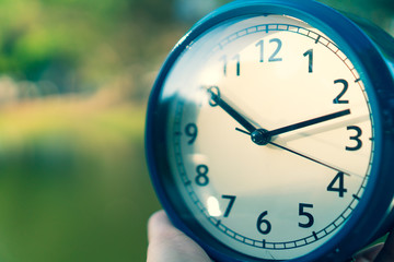 Selective focus of alarm clock with nature background.