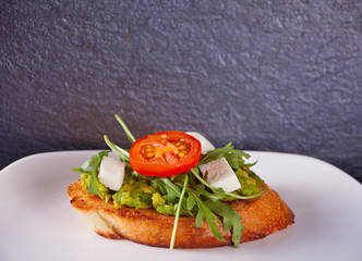 Sliced Toast Bread on white plate with tomatoes, feta and arugula