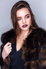 Beauty portrait of a woman with bright colorful make-up dressed in a fur coat