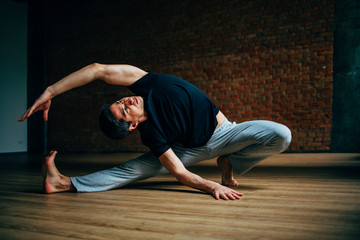 Fototapeta na wymiar Young man doing yoga in big bright training gym