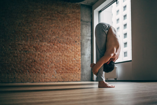 Young Man Doing Yoga In Big Bright Training Gym