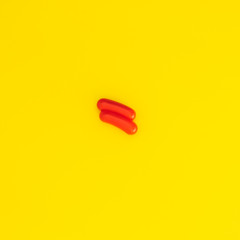 Red sausage on a yellow background. Minimalism and Breakfast.