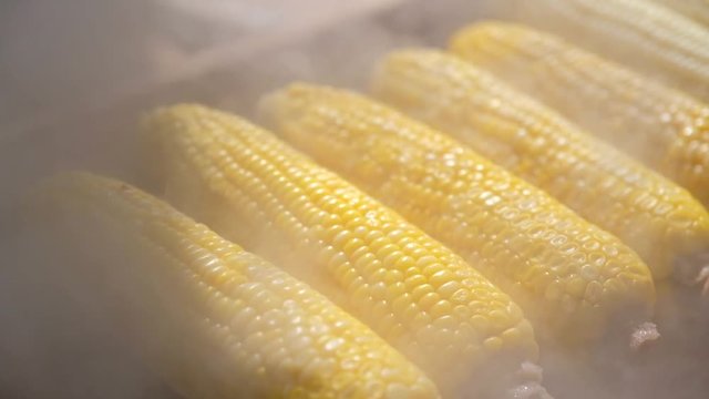 Close up of appetizing grilled sweet corn on the bbq grill. Street food festival in japan. Slow motion-the smoke from cooking movement