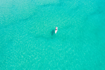 View from above, stunning aerial view of an unidentified person doing stand up paddle board on a...