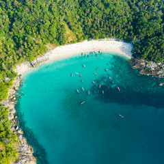 View from above, stunning aerial view of a beautiful tropical beach with white sand and turquoise clear water, long-tail boats and people sunbathing, Freedom beach, Phuket, Thailand.