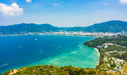 Fototapeta na wymiar View from above, stunning aerial view of Patong city skyline in the distance and the beautiful Tri Trang Beach bathed by a turquoise and clear sea in the foreground, Phuket, Thailand.